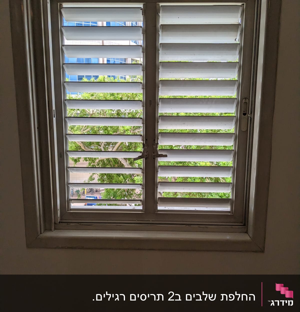 חלון עם תריסים לבנים פתוחים חלקית